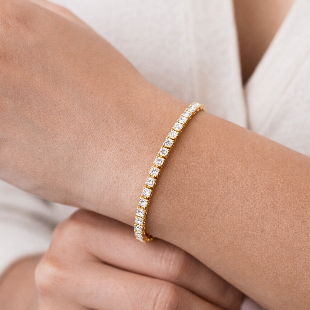 Gold bracelet with diamonds on a wrist against a neutral background
