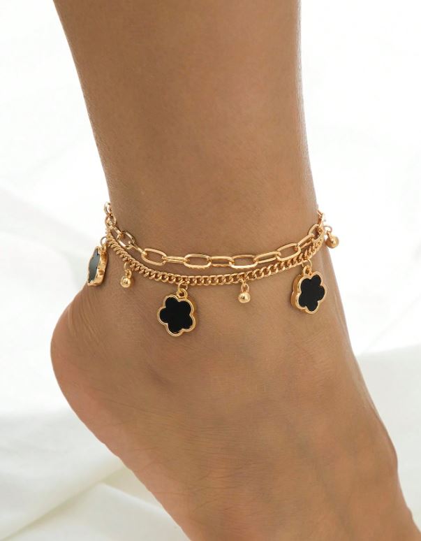 Gold anklet with black flower charms on a white background