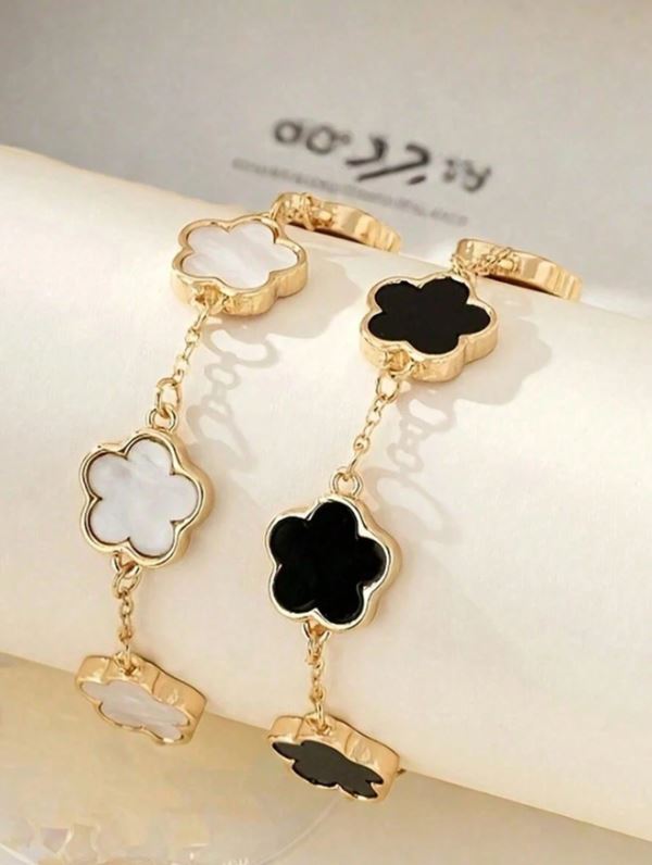 Gold bracelet with black and white clover-shaped charms on a light background