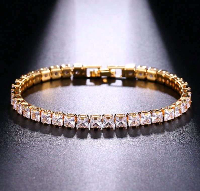 Gold bracelet with clear stones on a reflective surface