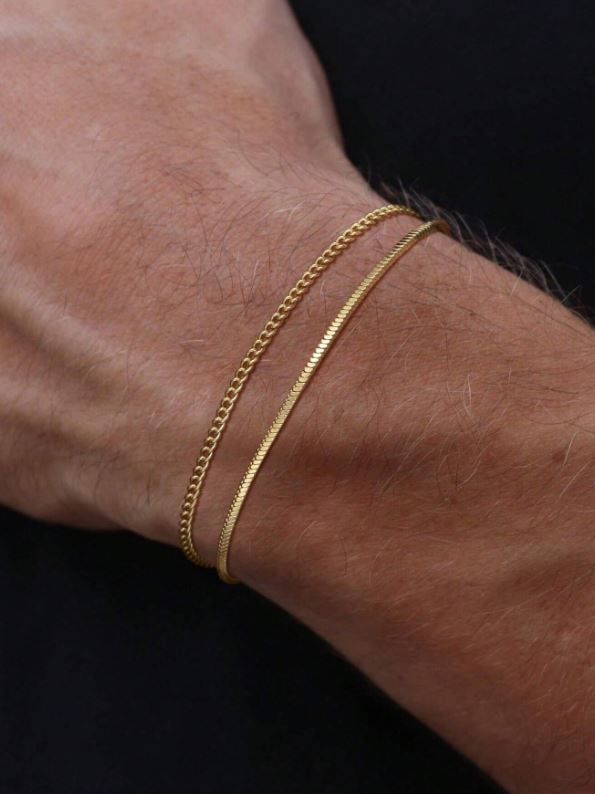 Gold chain bracelet on a wrist against a black background