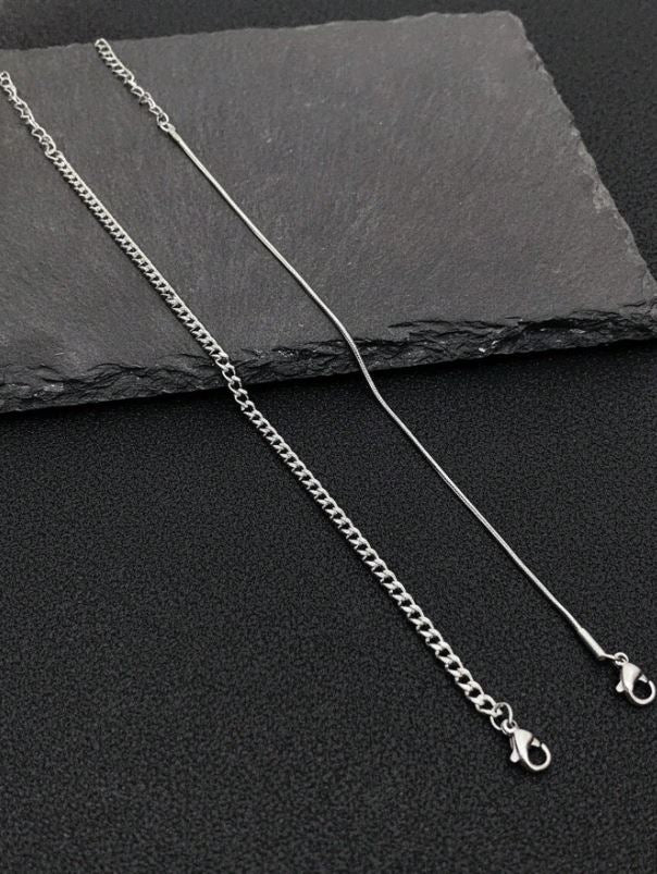 Silver chain necklace on a dark slate surface