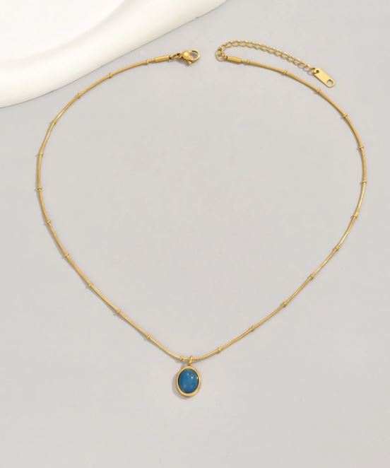 Gold necklace with a blue pendant on a light gray background