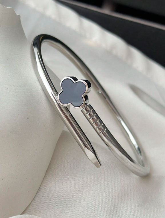 Silver bracelet with a clover-shaped charm on a white fabric background